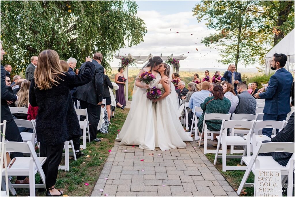 Two brides kissing. Purple wedding flowers