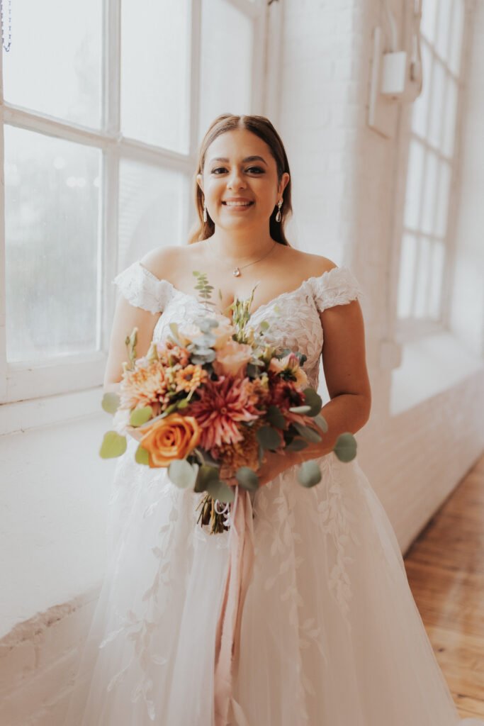 bride holding orange fall wedding flowers